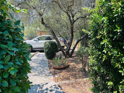a car is parked in a garden with trees at Beautiful studio in a secure private residence in Taradeau