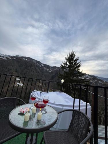 a table with two glasses of wine on a balcony at Turo House Meris in Inasharidzeebi