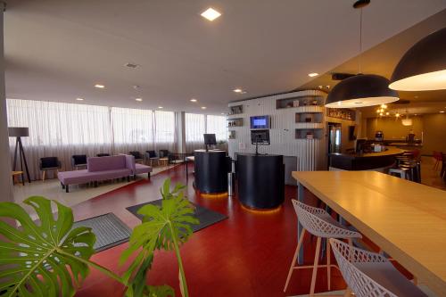 an office lobby with a bar and chairs and tables at Golden Tower Express Franca by Fênix Hotéis in Franca