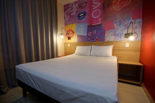 a bedroom with a large bed with white sheets at Golden Tower Express Franca by Fênix Hotéis in Franca