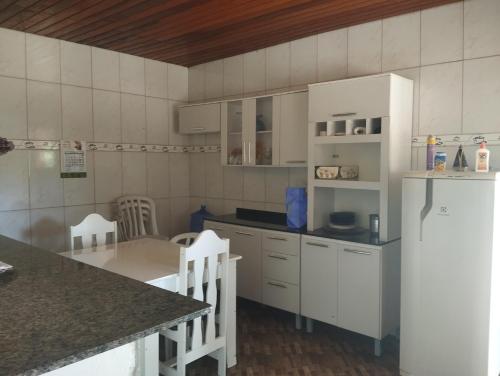 a kitchen with white cabinets and a table at Chácara Lopes in Cambuí