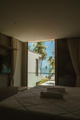 a bedroom with a bed with a view of the beach at Casa Believe Milagres in Passo de Camarajibe