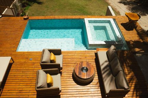 eine Holzterrasse mit einem Pool mit Stühlen und einem Tisch in der Unterkunft Casa Believe Milagres in Passo de Camarajibe