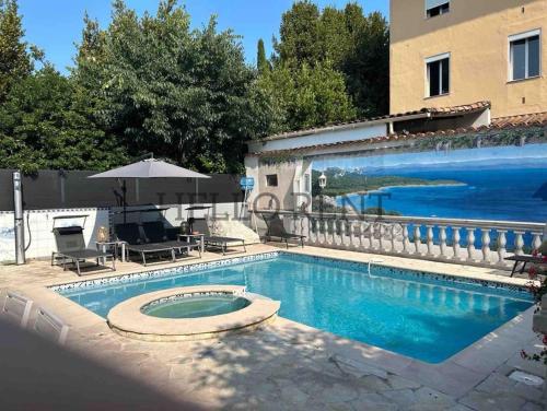 - une piscine avec un parasol à côté d'un bâtiment dans l'établissement Grande Villa Cannes Centre havre de paix, à Cannes