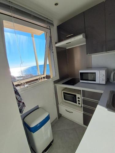 une petite cuisine avec un four micro-ondes et une fenêtre dans l'établissement studio face à la mer, à Sainte-Maxime