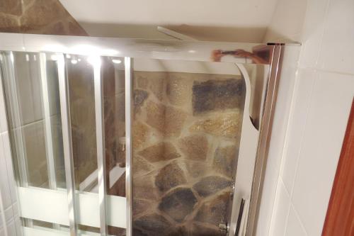 a shower in a bathroom with a stone wall at Cozy apartment in Collado Villalba 100 m² with open garden in Collado-Villalba