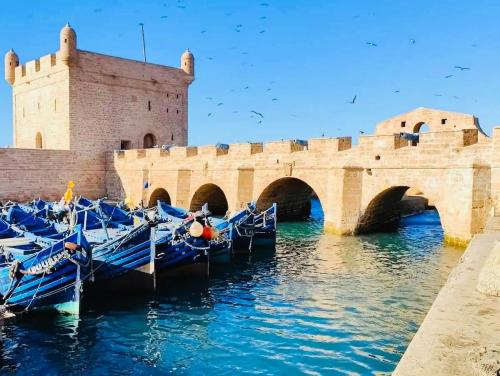 un groupe de bateaux bleus dans l'eau près d'un pont dans l'établissement RELAXING EXPERIENCE In ESSAOUIRA-VILLA OLIVE, à Essaouira