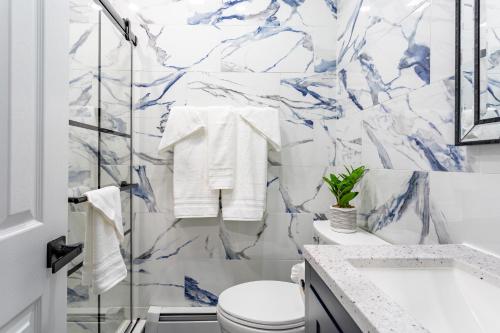 a bathroom with a white toilet and a marble wall at Comfort Meets Style 3BR Plus Parking in New Rochelle