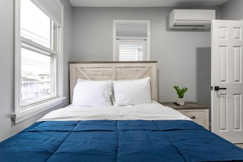 a bedroom with a blue and white bed with a window at Comfort Meets Style 3BR Plus Parking in New Rochelle