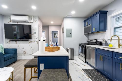 a kitchen with blue cabinets and a blue couch at Comfort Meets Style 3BR Plus Parking in New Rochelle