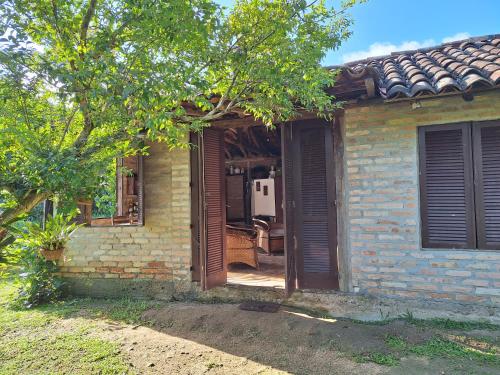 an open door of a brick house with a tree at Casa rústica divertida in Florianópolis