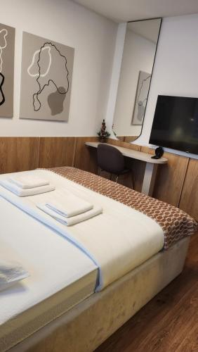a bedroom with a bed and a desk with a television at Apartmani Dobrinja - Free parking- Rent a car in Sarajevo