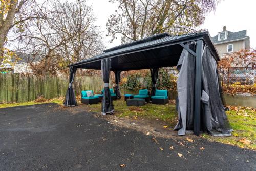 a black gazebo with blue chairs under it at Comfort Meets Style 3BR Plus Parking in New Rochelle