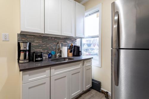 a kitchen with white cabinets and a stainless steel refrigerator at Upscale Relax 2 Bedroom near Yankee Stadium 14 min drive in New Rochelle