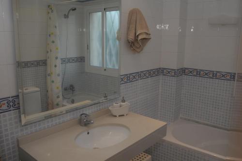 y baño con lavabo, bañera y espejo. en Apartaments Villa Conchi, en Sitges