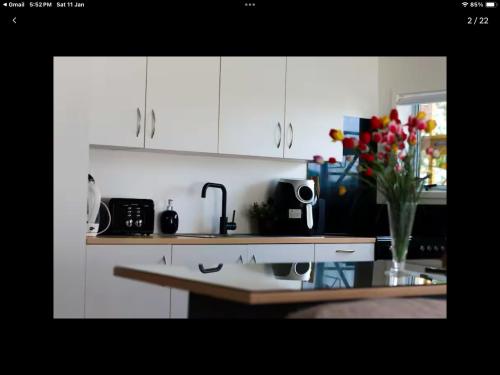 a kitchen with white cabinets and a vase of flowers at Modern and spacious 1-Bedroom Holiday Home in Whangarei