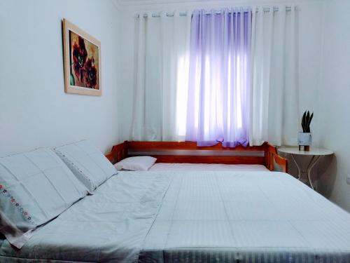 a bedroom with a large white bed in front of a window at Casa de campo rocha in Ribeirão Pires