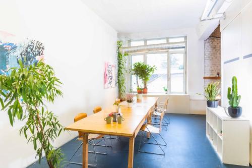 a dining room with a table and some plants at 200 qm LOFT am Fluss für Freunde und Familien ! in Berlin