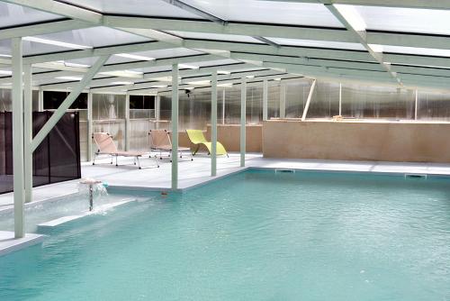 une piscine d'eau avec des chaises dans un bâtiment dans l'établissement Maison accueillante avec vue sur le lac à Moncoutant, à Moncoutant