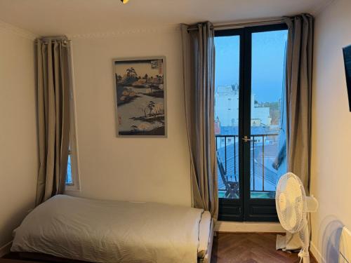 une chambre avec un lit et une grande fenêtre dans l'établissement Fantastic apartement & terrace Paris Montparnasse, à Paris