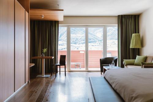 a hotel room with a bed and a large window at Lindenhof Pure Luxury & Spa DolceVita Resort in Naturno