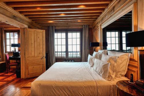 a bedroom with a bed and a desk and windows at Le Saint Joseph in Courchevel