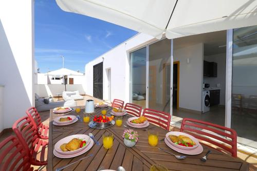 a wooden table with plates of food and orange juice at Casa Frangipani, Quinta da Foz in Tavira