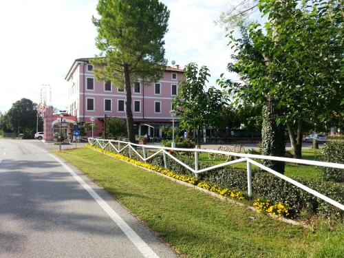 a white fence in front of a pink building at Dogana Vecchia - Hotel & Residence B&B Ristorante & Pizzeria in Trivignano Udinese
