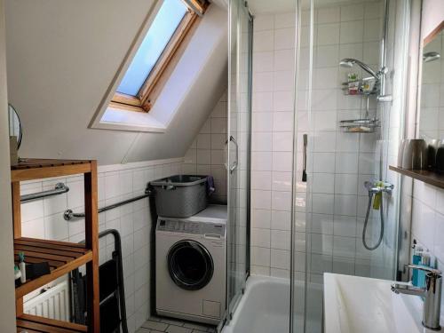 a bathroom with a shower and a washing machine at Cozy holiday home in Sint Maartenszee in Sint Maartenszee