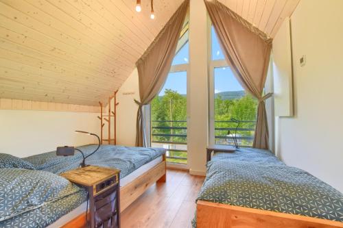 two beds in a room with a window at Osada Pod Maliną in Brenna