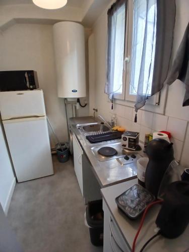 Il comprend une petite cuisine équipée d'un réfrigérateur blanc et d'une cuisinière. dans l'établissement Detente, à Paris
