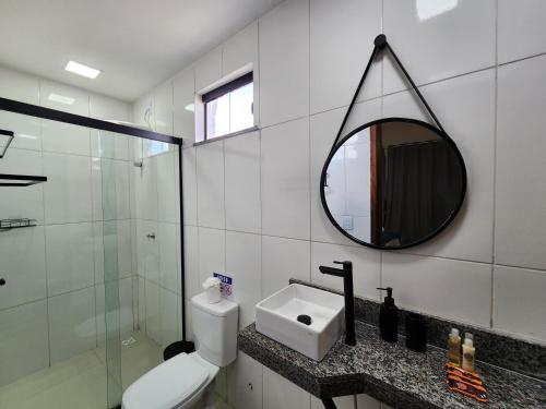a bathroom with a toilet and a sink and a mirror at Pousada Ville Solare - Santo Amaro in Santo Amaro