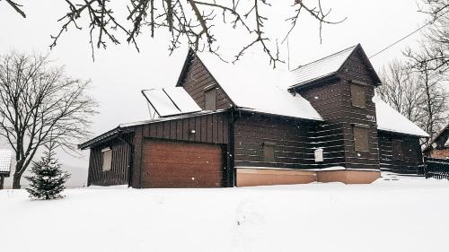 a building with snow on the roof of it at Beskidzki Domek Kurów in Kurów