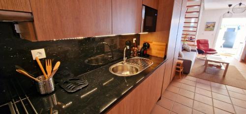 eine Küchentheke mit zwei Spülbecken und ein Wohnzimmer in der Unterkunft Casa en El Pedroso de tres habitaciones in El Pedroso