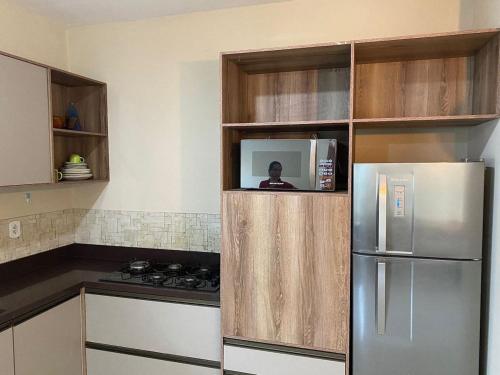 a kitchen with a refrigerator and a person in a microwave at Casa Refúgio do Vale *Unimed* in Volta Redonda