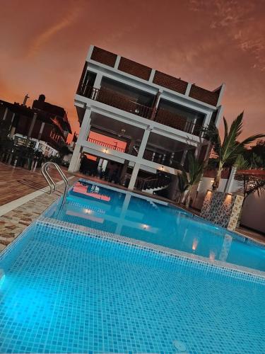 a hotel with a swimming pool in front of a building at Oliver's Garden Country Hotel in Chincha