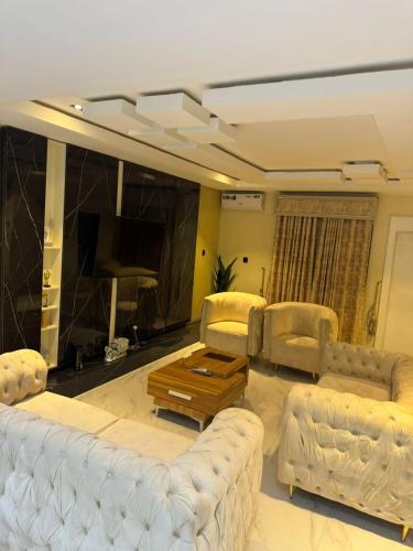 a living room with white couches and a piano at Ayahs Court in Abuja