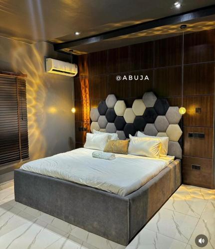 a bedroom with a large bed with aania sign on the wall at Ayahs Court in Abuja