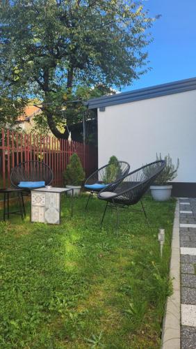 three chairs and a table in a yard at Apartmani Dobrinja - Free parking- Rent a car in Sarajevo