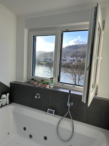 a bath tub in a bathroom with two windows at Weingut-Gästehaus-Haas in Zell an der Mosel