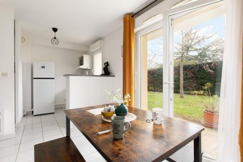une cuisine avec une table en bois et une grande fenêtre dans l'établissement Le Tamaris, calme avec terrasse, à Colomiers