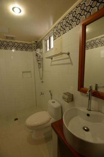 ein Badezimmer mit Toilette, Waschbecken und Spiegel in der Unterkunft Abozza Resort in Boracay