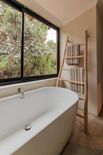 a bath tub in a bathroom with a window at Induli Lodge - Amakhala Game Reserve in Amakhala Game Reserve
