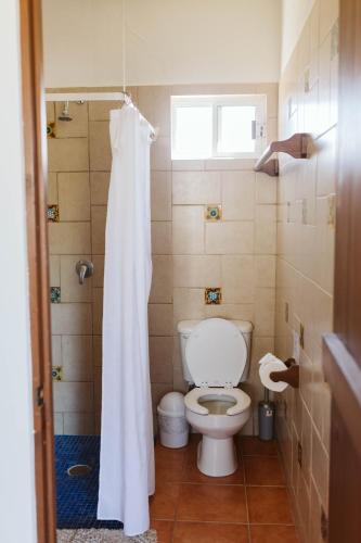 a bathroom with a toilet and a white shower curtain at Olas de Cerritos in El Pescadero