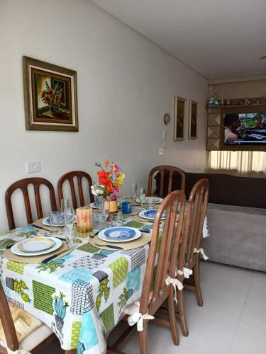 a dining room with a table with chairs and a table cloth at sobrado 08 com duas suítes, conf in Guarujá