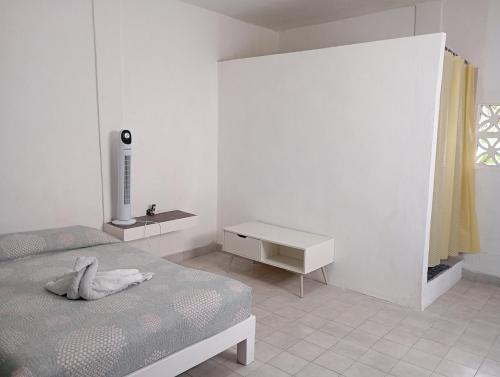 a white bedroom with a bed and a night stand at Quartito en la Noria with terrace in Zihuatanejo