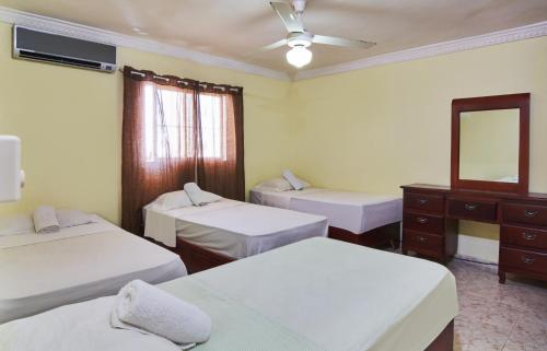 a room with three beds and a mirror and a dresser at BNB Family Vacation Rentals, Corales del Sur, Santo Domingo Este in La Viva