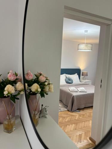 a mirror reflection of a bedroom with a bed and flowers at Atmosfera Sibiu in Sibiu