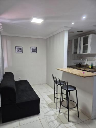 a living room with a black couch and chairs at Sossai Hostel Flats in Vitória