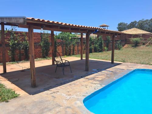 a pergola with a chair and a swimming pool at Espaço Pegoraro in Cianorte
